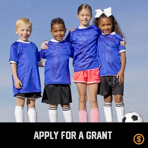 Multicultural diverse coed youth sports soccer players with arms around each other with a soccer ball