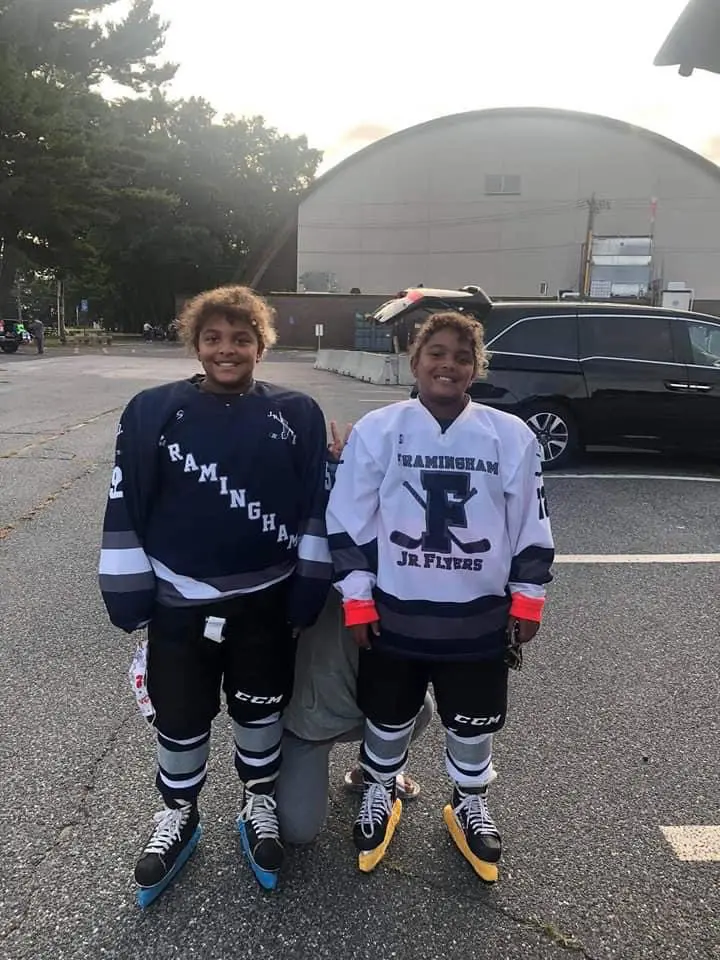 Two twin girl youth hockey players in hockey uniforms and gear