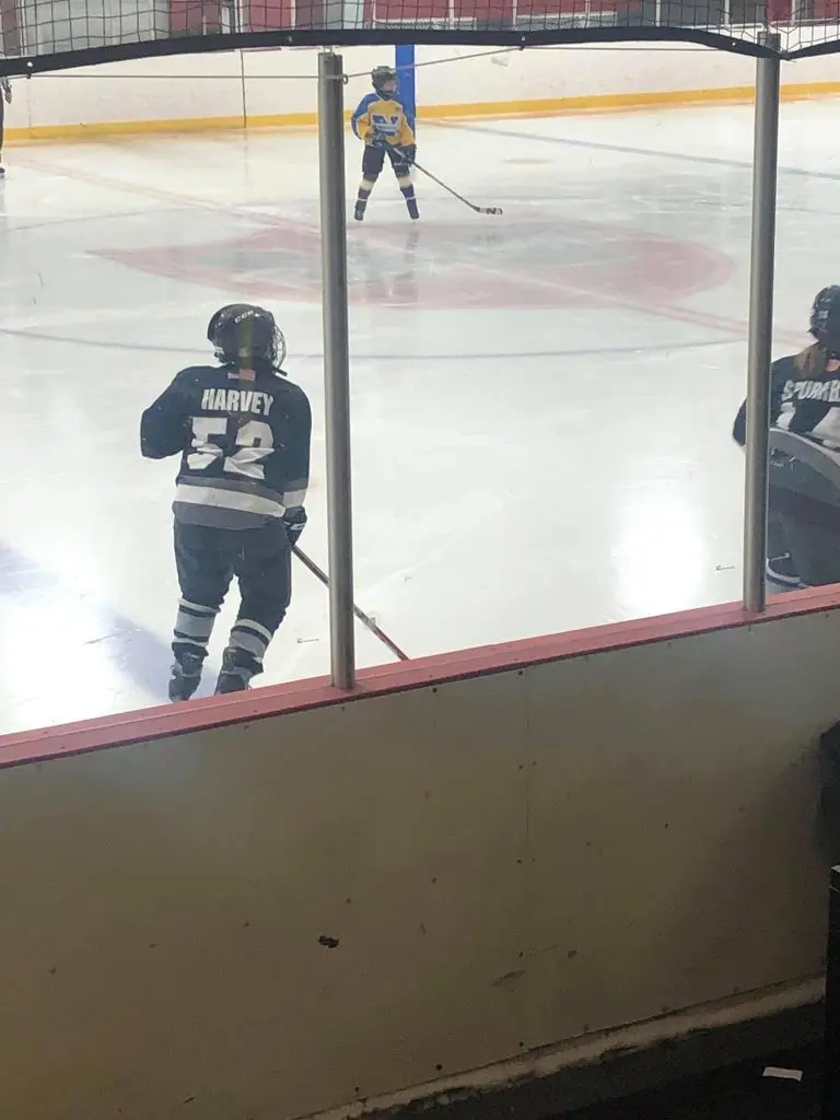 Girl youth hockey player skating on hockey rink ice with hockey stick