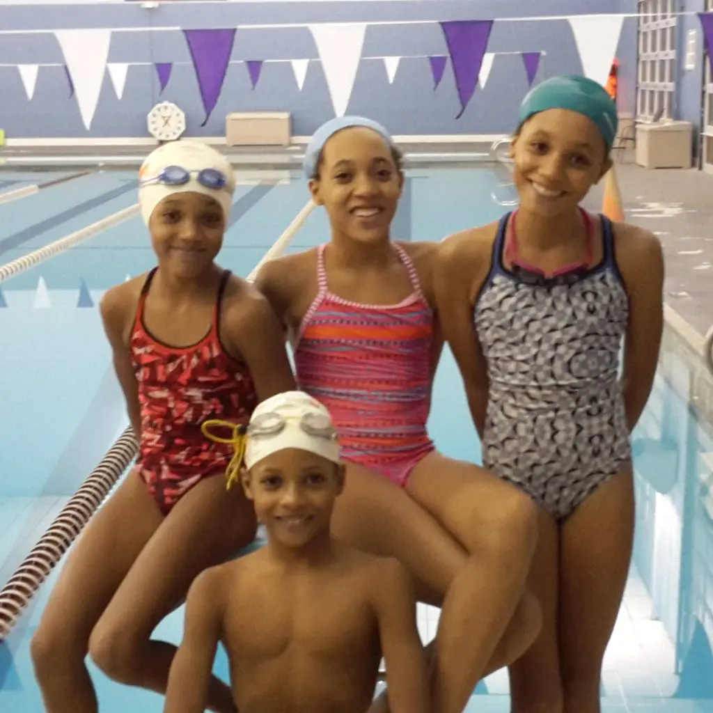 Four competitive swimming kids near pool with All Kids Play youth sports financial assistance grant