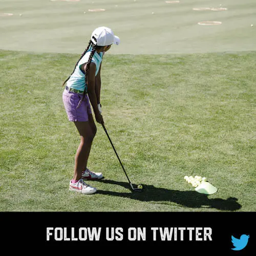 African American youth sport girl golfer teeing up to swing and hit a golf ball on a golf course