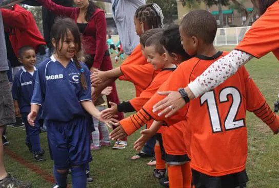 Coed multicultural diverse youth sports soccer teams shaking hands after a soccer match