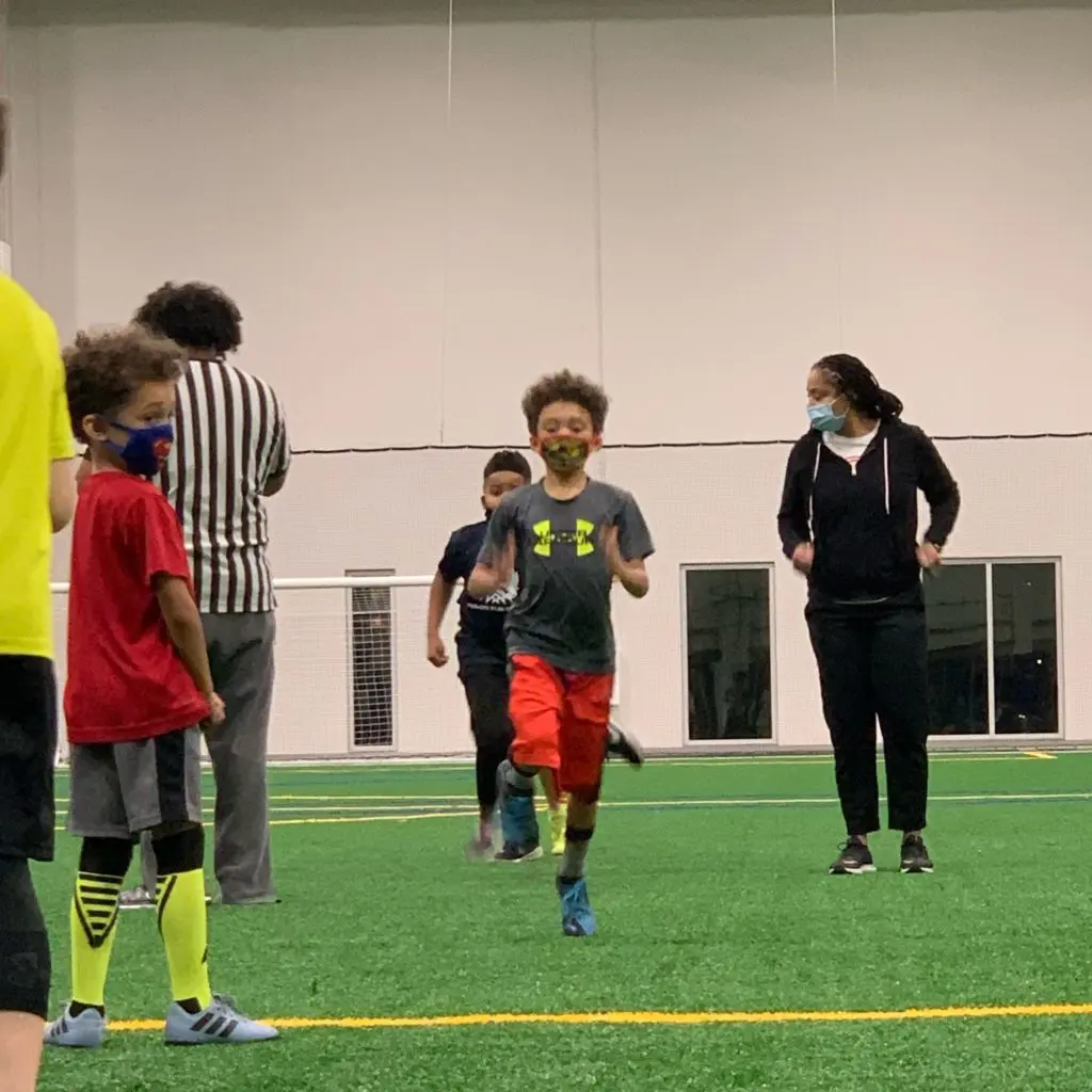 Brother flag football players running indoors on turf at practice with All Kids Play youth sports grant