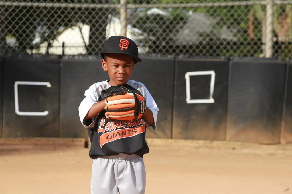 African American boy youth athlete on playing baseball with glove on baseball field
