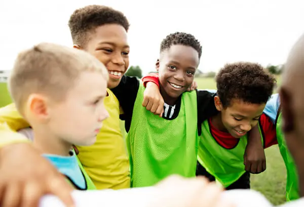 African American boy youth sports soccer players in a huddle happy to be part of a team