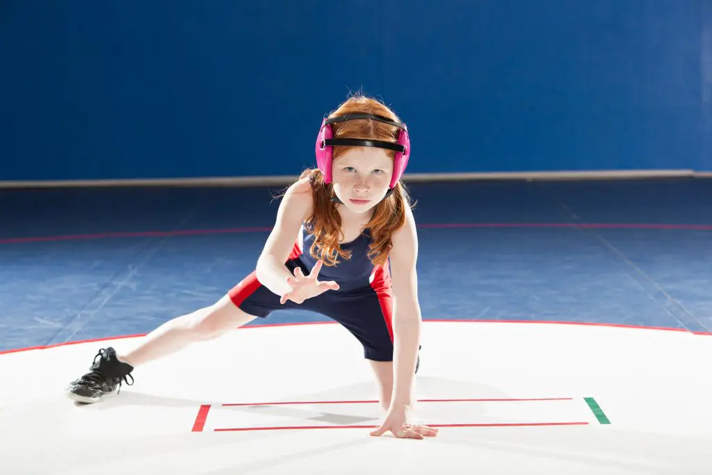 Girl youth sports wrestler on wrestling mat warming up
